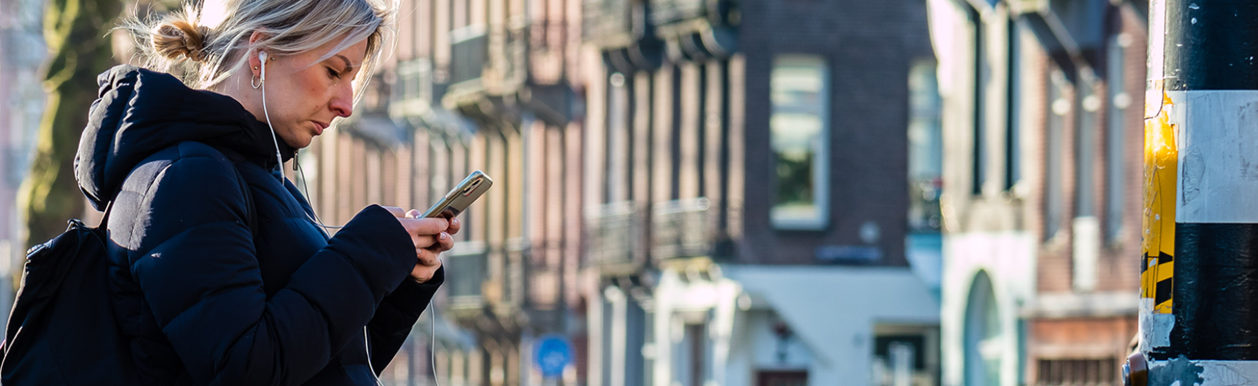Mevrouw op haar telefoon bij oversteekplaats