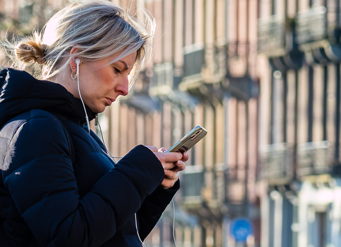 Mevrouw op haar telefoon bij oversteekplaats